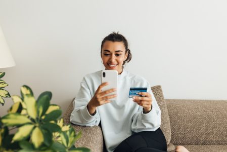 Smiling woman using smartphone and credit card. Young female making a purchase online. Smiling woman using smartphone and credit card. Young female making a purchase online.