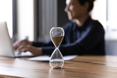 Close up hourglass measuring time, Indian businesswoman working Close up hourglass measuring time, Indian businesswoman working