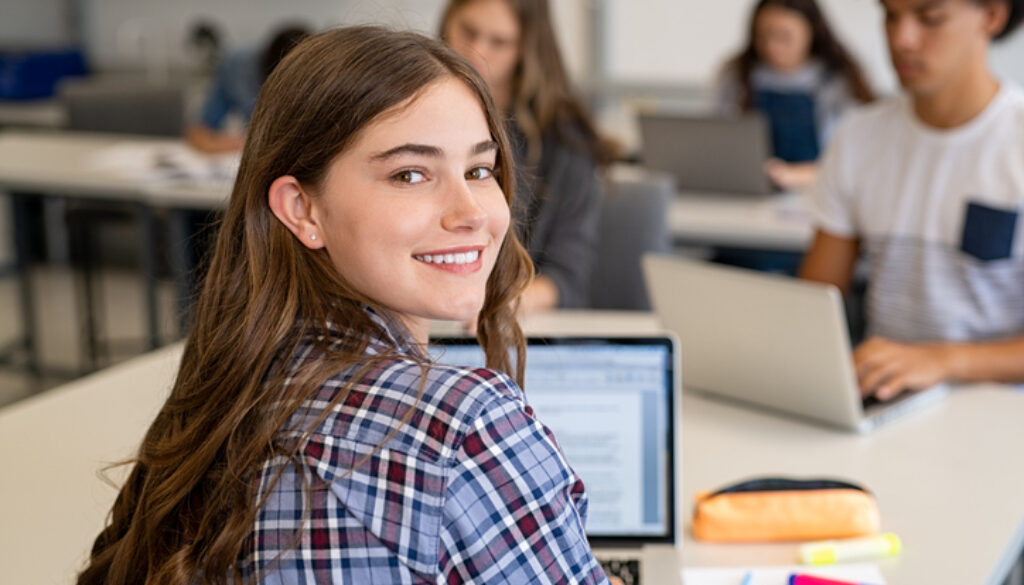 Happy smiling college girl studying on laptop